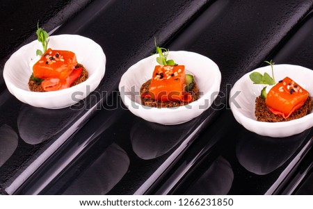 Giving of fish on black bread with sesame