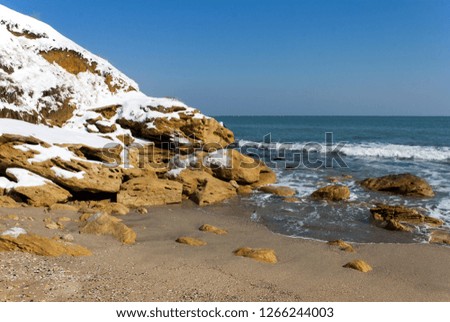 Winter sea view in the village of Ravda, Bulgaria. January snow on sea rocks.