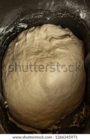 Fluffy raw dough in metal black pan for bread maker