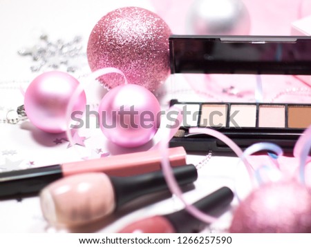 Women's Christmas cosmetic set, color correction powder for the face with eye shadows and gift box on pink background,  decorated Christmas balls, bow and shining stars.