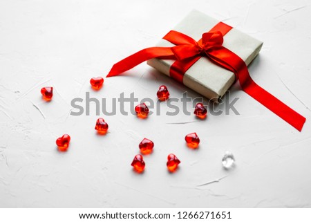 Red plastic hearts and a gift-box with ribbon are on twhite background. St. Valentine's Day concept.