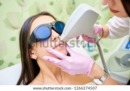 Doctor cosmetologist conducts the procedure of laser hair removal from the body of a girl. Laser hair removal. Cosmology. Facial hair removal Royalty-Free Stock Photo #1266274507