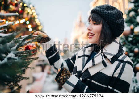 Portrait of young brunette near painted Christmas tree on street