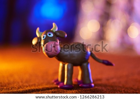 merry plasticine cow from Christmas series on blurred background