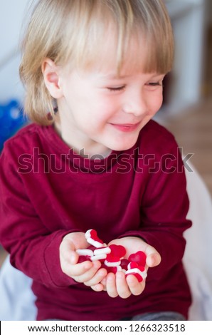 sweet little candies red hearts in the hands of a little smiling boy