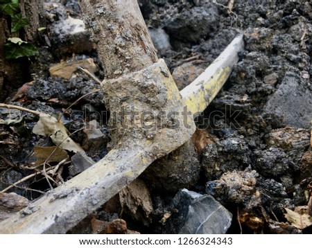 Yellow pickaxe with mud on the metal part.