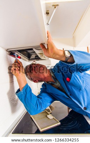 Mature laborer is working hard and fixing installation in vent hood