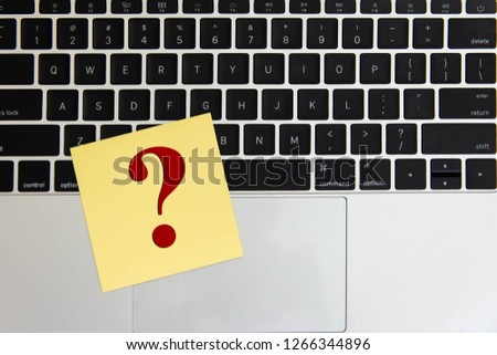 Question mark symbol post it on keyboard computer white table background.    
Alphabet Questions and Answers or Q&A note paper on laptop wood desk background.
top view.