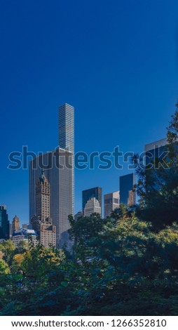 View of buildings and skyscrapers of midtown Manhattan above trees, viewed from Central Park of New York City, USA