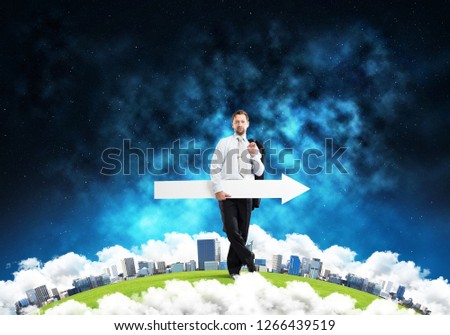 Conceptual image of young successful business man in suit pointing aside by means of big white banner in form of arrow while standing on Earth globe. Elements of this image are furnished by NASA.