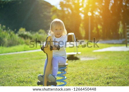 little girl is having fun at rocking horse at kids playground