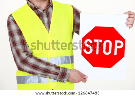 A cropped picture of a road worker holding a stop sign.