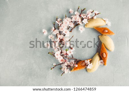 Novruz wreath made of traditional Azerbaijan pastry shekerbura and pakhlava, beautiful tiny blossoms for spring equinox celebration on grey background, flat lay top view copy space for text for nowruz