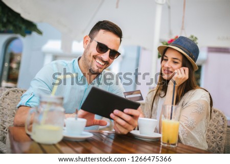 Happy young couple shopping online while sitting in a cafe. 