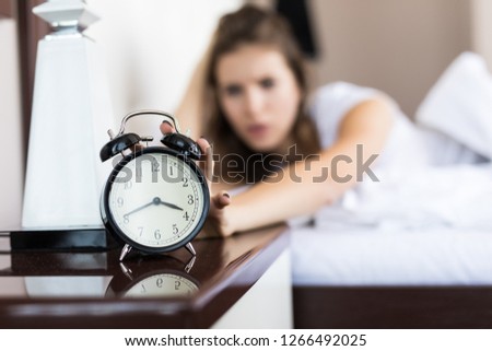 Happy woman waking up and turning off the alarm clock having a good day