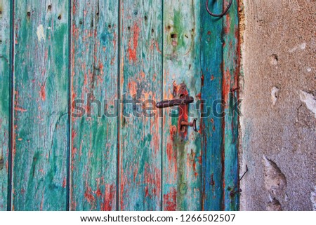 an old door with green peeling paint and a keyhole from which a broken key juts out