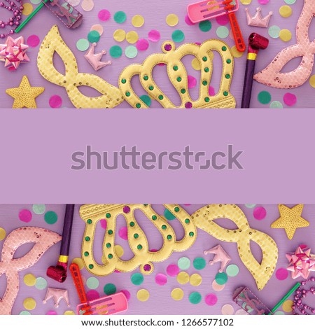 Purim celebration concept (jewish carnival holiday) over purple, pink wooden background. Top view