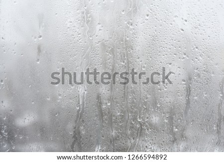 
Drops of water on the window pane on the background of the snow-covered city