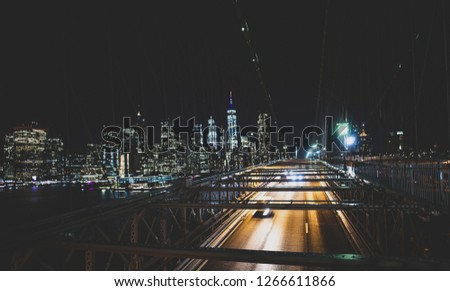 Long exposure picture of cars passing over the illuminated Brooklyn Bridge at night. Manhattan skyline in the background, New York city, USA.
