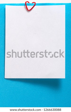 Empty sheet of  paper on a clip in the form of a heart. Blank for Valentine's Day Love Card, blue background
