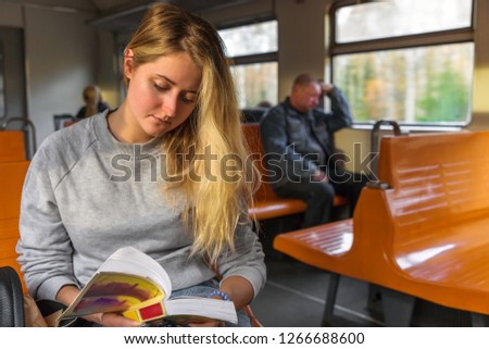 cute girl reading a book with interest while in the train.