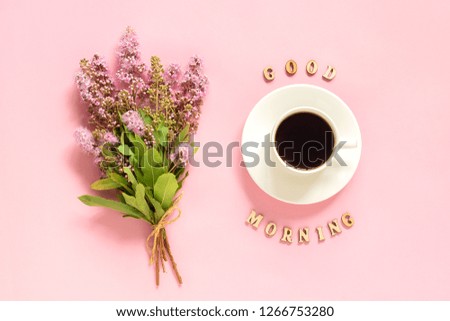 Bouquet of pink flowers, cup of coffee and text Good morning on pink background Greeting card Flat Lay Concept.
