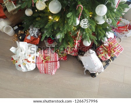 Christmas tree with modern floor and decoration full of gifts of different kind underneath picture taken from above.  