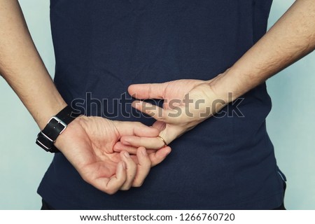 a man in struggling to remove wedding ring from his finger holding hands behind his back. concept of treason. Husband cheats on wife. cheating wife Royalty-Free Stock Photo #1266760720