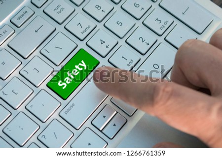 Closeup picture of Safety First button of a modern keyboard. A male finger presses a color button on a gray silver keyboard of a modern laptop. Button with inscription close up safety