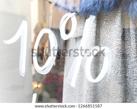 Ten percent sale (discount) hand written in white on the show-case of a store - arty design character