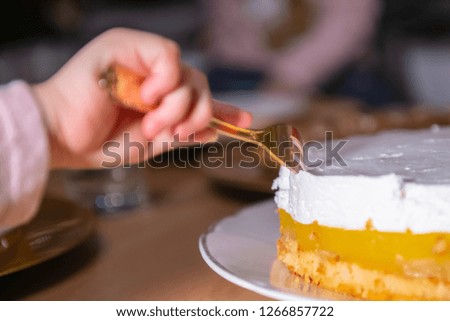 Child stealing a piece of cake reaching with fork into the sweet dessert, nobody
