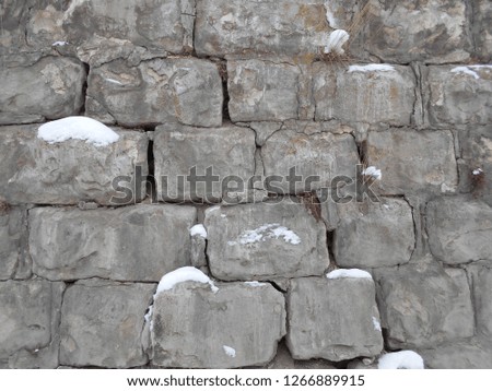 broken stone wall in the snow. cement in the winter in the cold. stock photo image