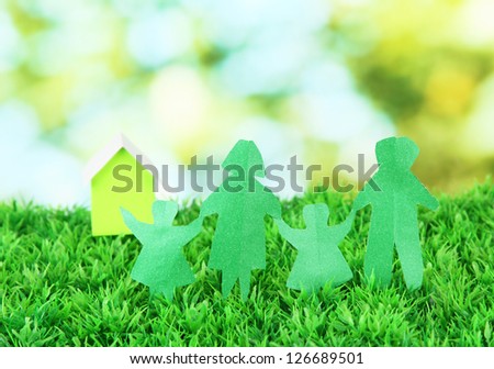 Paper people on green grass on bright background