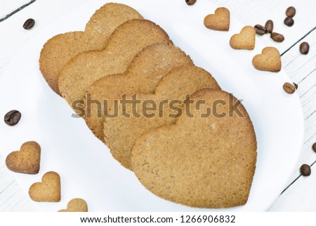 Plate of heart shaped cookies close up on white wooden background. Breakfast for Valentine's day.