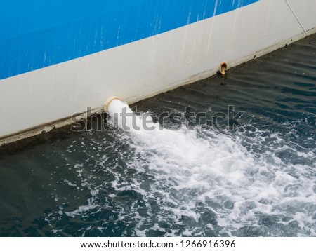 bilge water pumped out of the side of a ship in the water of the port 
 Royalty-Free Stock Photo #1266916396