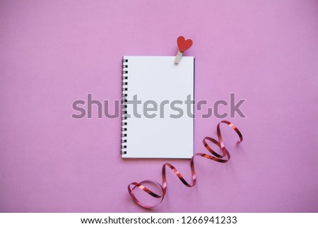Blank notepad with pin with a heart on a pink background. Festive concept of Valentine's Day or another love event in a minimal style.
