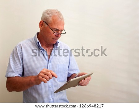 A man in his 60s with a pc tablet in his hand