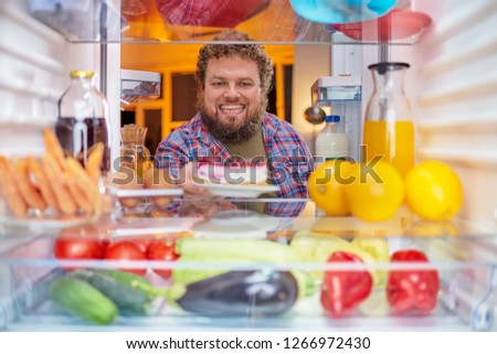 Man taking cheesecake from fridge. Picture taken form inside of fridge.