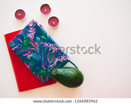 Top view workspace with avocado, diary, notebook, candles on white background