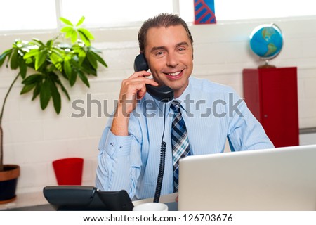 Smiling manager engaged in business interactions over a phone call.