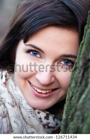 Portrait of the attractive smiling girl near the tree