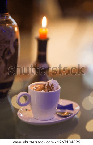 Porcelain glass of Viennese coffee, a vase of Dragon Greek style and candlestick with lighted candle, and boke