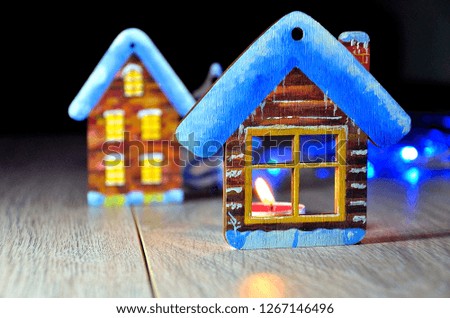 Homemade Christmas toys - a winter wooden house, a candle in the window, garlands.