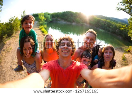 Selfie of friends on nature. Friends are resting near the lake. Great fun company. Big family gathered together on vacation. Children and parents on a picnic in the summer forest.