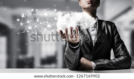 Businessman in suit keeping cloud with network connections in hand with office view on background.