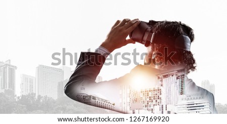 Double exposure of businessman in virtual helmet against cityscape background