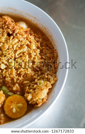 Coconut shrimp laksa soup on a grey background, top view. Laksa Telur Sarang meaning laksa with nest shaped egg. Famous in Perak,Malaysia.Copy space - Image