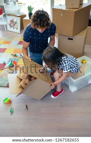 Little boy drawing in a moving box with his father