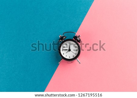 Vintage black alarm clock on a color block background