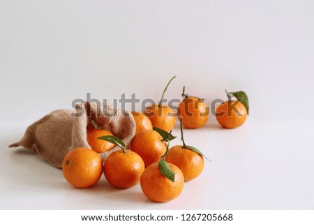 Fresh raw organic Tangerines  with green leaves in bag on white wooden table.Copy space . Rich of nutrients, fiber, and vitamins. Picture design for foods background.